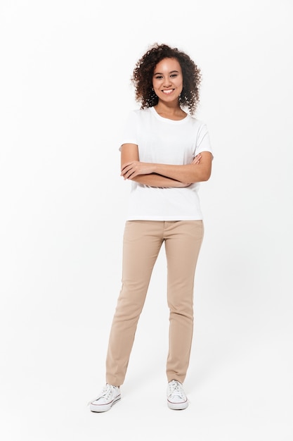 Full length of a happy young african woman wearing casual clothes isolated over white wall, arms folded