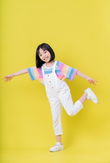 Full length image of Asian child posing on yellow background