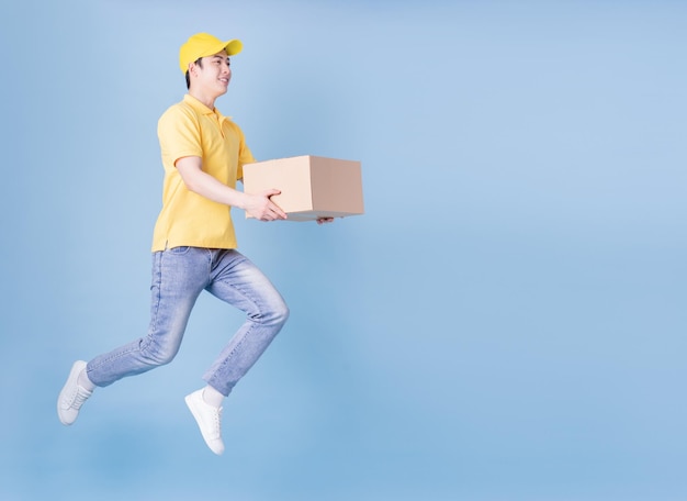 Full length image of Asian delivery man on blue background