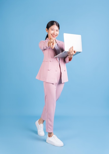 Full length image of young Asian business woman on background