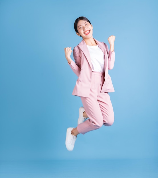 Full length image of young Asian business woman on background