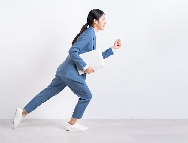 Full length image of young Asian businesswoman holding laptop