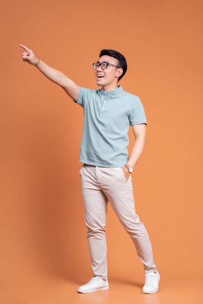 Full length image of young Asian man standing on backgound