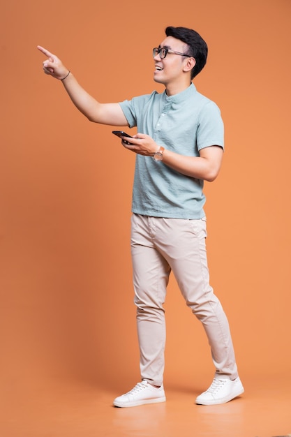 Full length image of young Asian man standing on backgound