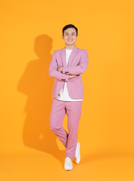 Full length image of young Asian man standing on orange background