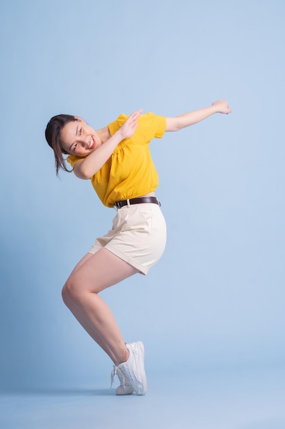 Full length image of young Asian woman posing on blue background