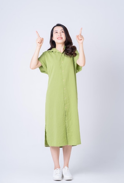 Full length image of young Asian woman wearing green dress on background