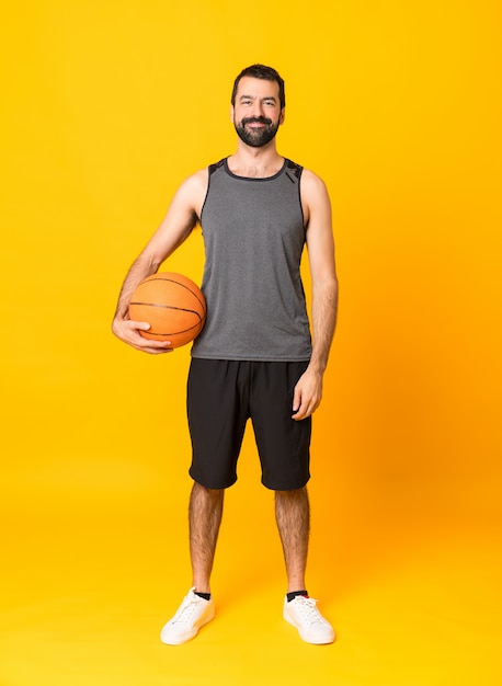 Full length  man over isolated yellow wall playing basketball