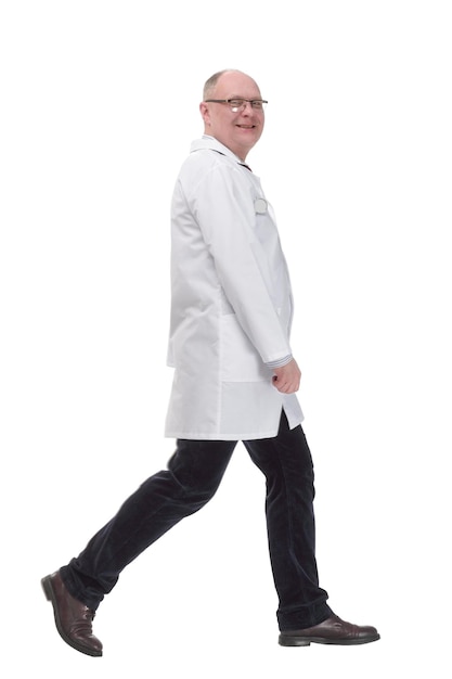 Full-length. mature doctor in a white coat striding forward .isolated on a white background.