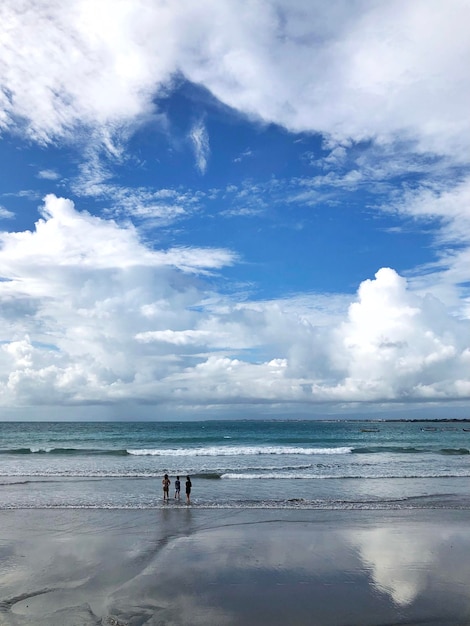 Full length of people standing on beach against sky