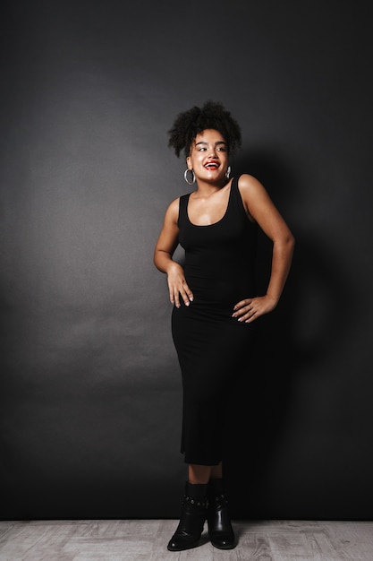 Full length photo of adorable afro american woman wearing black dress standing