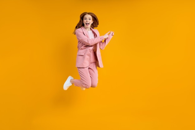 Full length photo of funny caucasian lady in pink suit jumping up high see low shopping prices direc...