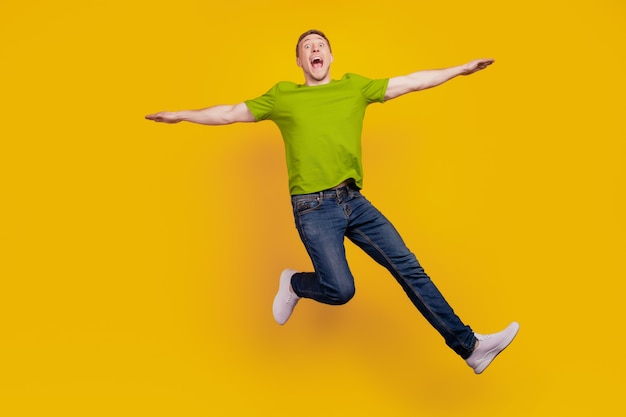 Full length photo of nice attractive cheerful optimistic guy having fun jump up fly air plane isolated over yellow background