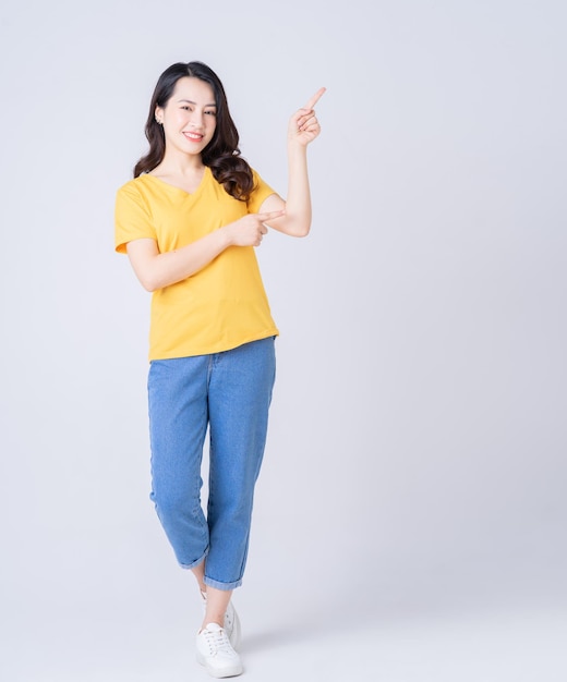 Full length photo of young Asian woman standing on white background