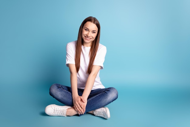 Full length photo of young pretty woman good mood sit floor enjoy weekend isolated over blue color background