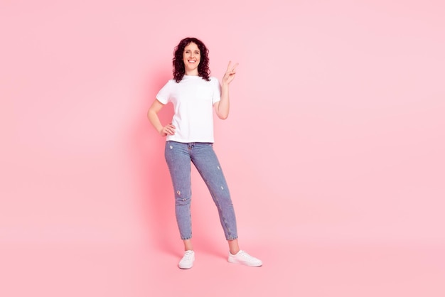 Full length photo of young woman show fingers peace cool v-symbol isolated over pink color background