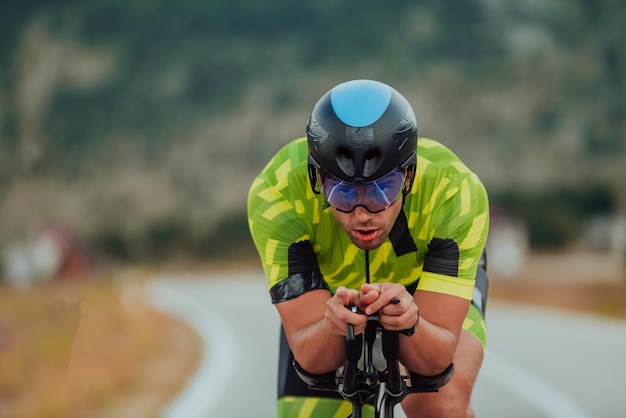 Full length portrait of an active triathlete in sportswear and with a protective helmet riding a bicycle. Selective focus.