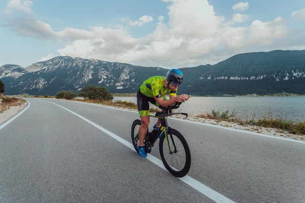 Full length portrait of an active triathlete in sportswear and with a protective helmet riding a bicycle. Selective focus.