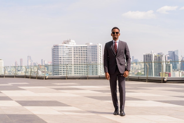 Full length portrait of African businessman wearing suit and tie outdoors in city while standing