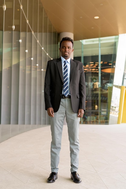 Full length portrait of African businessman wearing suit and tie outdoors in city