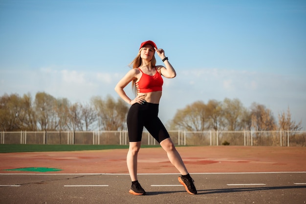 Full length portrait of athletic sportswoman posing at the sports ground stadium in spring