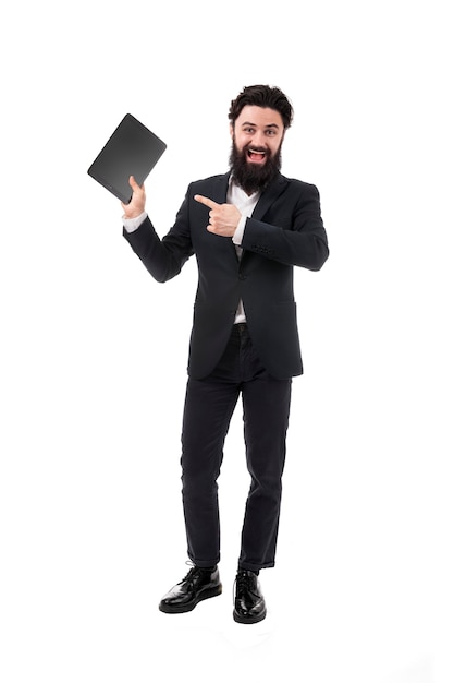 Full length portrait of bearded businessman with tablet in hand, man pointing on blank tablet screen, isolated on white wall