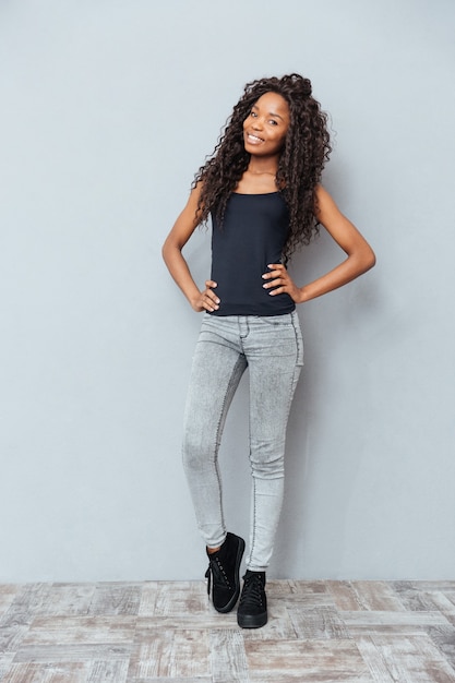 Full length portrait of a beautiful woman posing on gray wall