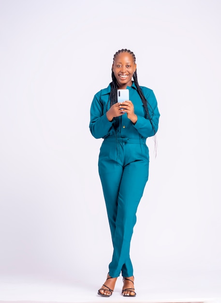 Full length portrait of a black african young business woman with a cell phone standing over excited