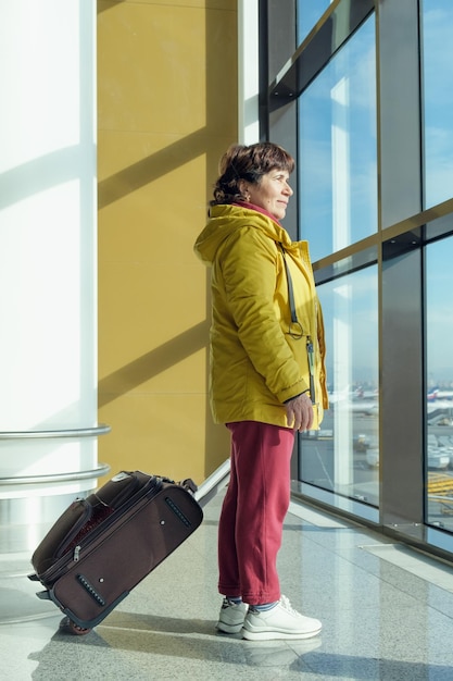 Full length portrait of an elderly woman with a suitcase