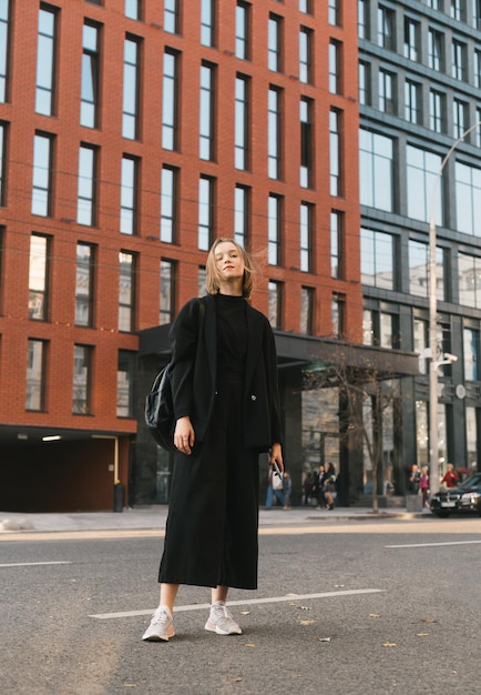 Full length portrait of a fashionable girl outdoors on the background of modern architecture