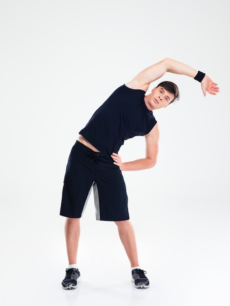 Full length portrait of a fitness man doing stretching exercises isolated