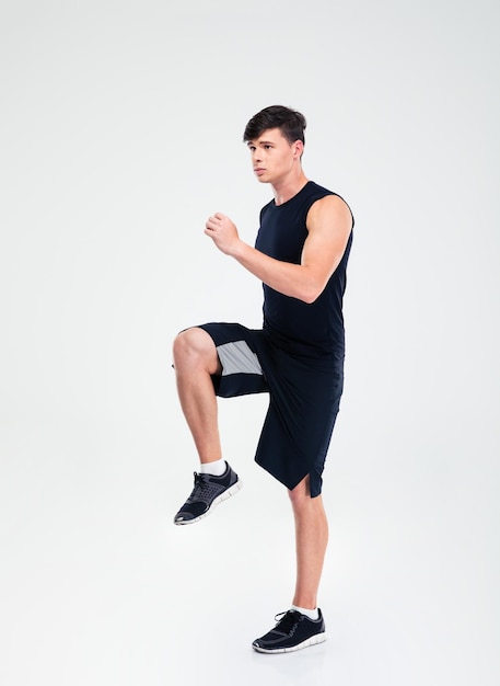 Full length portrait of a fitness man doing warm up exercises isolated