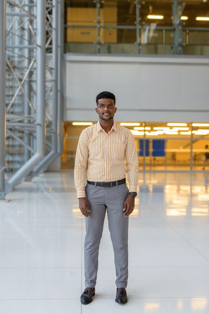 Full length portrait of handsome African man at airport terminal traveling during covid