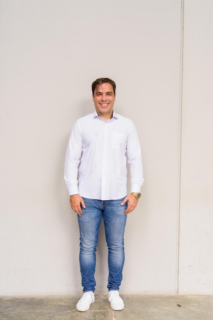 Full length portrait of handsome Persian man smiling against plain background