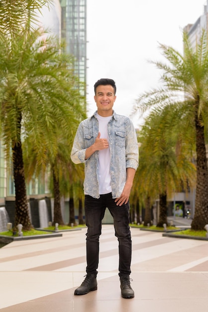 Full length portrait of handsome young man outdoors in city during summer