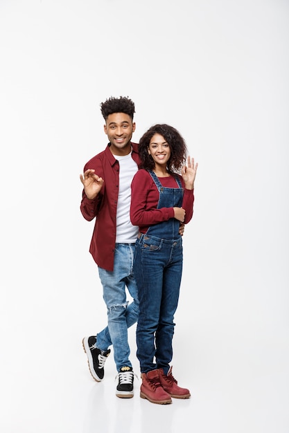 Full length portrait of a happy smiling african couple standing and showing ok gesture.