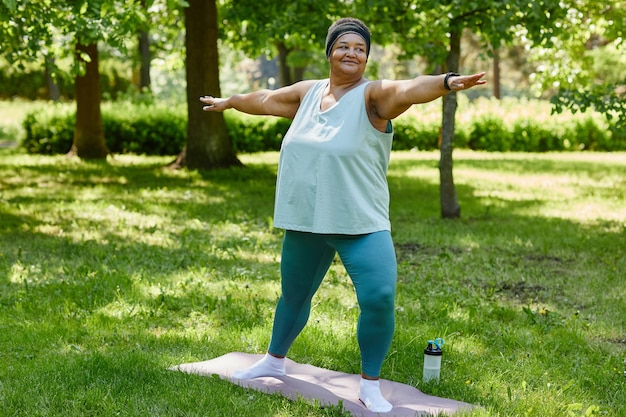 Full length portrait of overweight black woman working out outdoors in park and smiling copy space