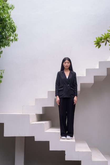 Full length portrait of a professional woman in business attire exuding confidence on modern architectural steps