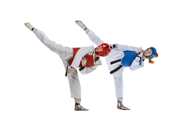 Full-length portrait of two professional taekwondo feale athletes fighting isolated over white background