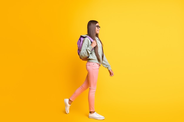 Full length portrait of young person go carry backpack wear hoodie isolated on vibrant yellow color background