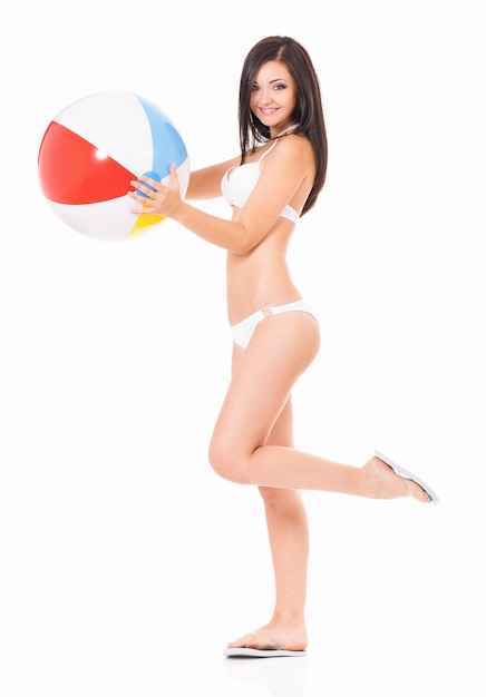 Full length portrait of young woman in a white bikini with beach ball isolated on white background