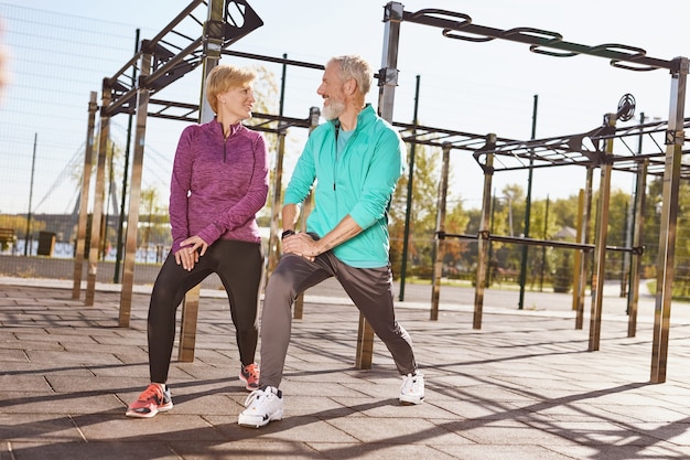 Full length of senior or mature happy couple in sportswear exercising together in the early morning