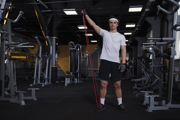 Full length shot of an athletic man doing shoulders exercise using resistance band