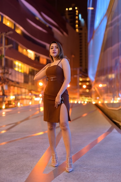 Full length shot of beautiful Asian woman outdoors in Bangkok, Thailand at night