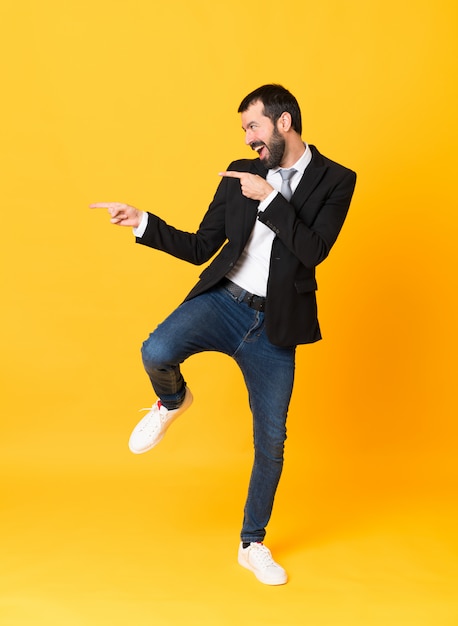 Full-length shot of business man pointing to the lateral over isolated yellow