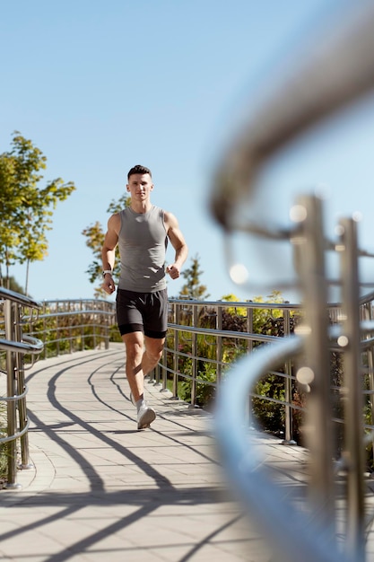 Full length shot of man in sportswear running and looking straight during the summer