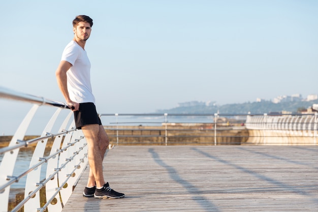 Full length of thoughtful young sportsman standing outdoors and thinking