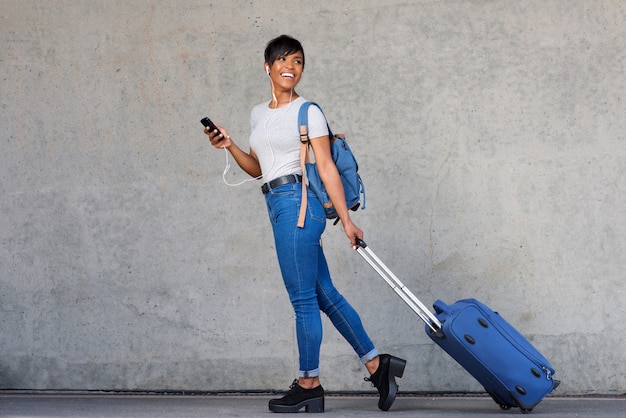 Photo full length traveling young woman with mobile phone and suitcase