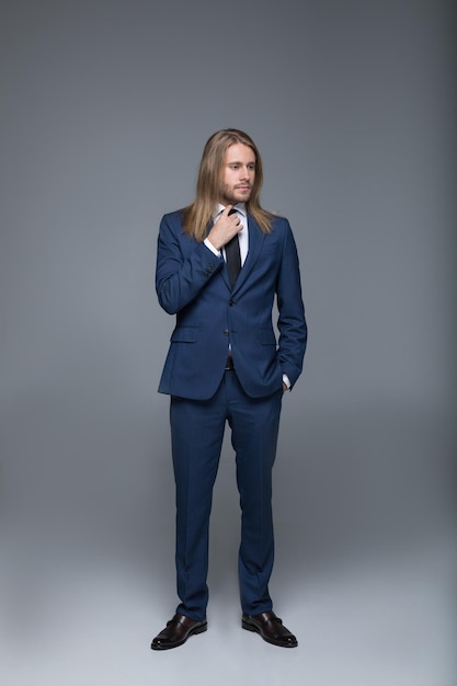 Full length view of handsome long haired man wearing stylish suit and looking away