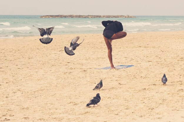 Photo full length of woman doing yoga at beach